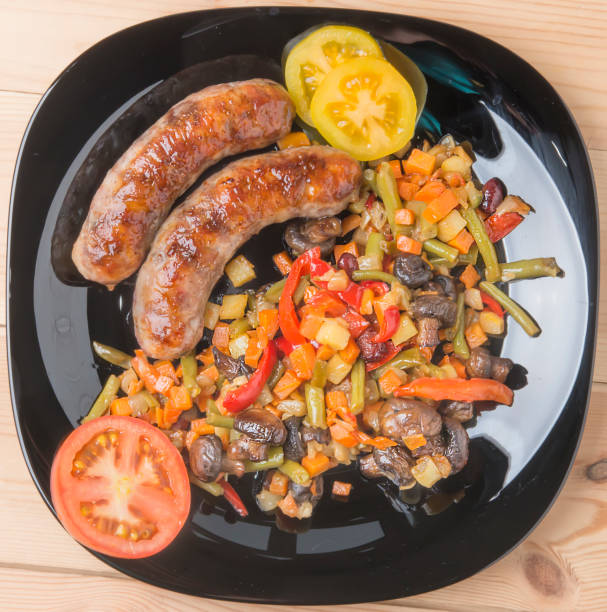 istock Fried sausages with vegetables on a kitchen table with tomatoes 675341506
