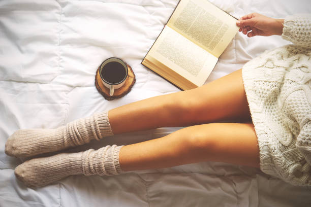 Photo douce de la femme sur le lit avec livre et tasse de café, vue de dessus - Photo