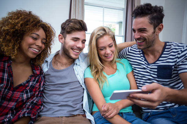 istock Young friends looking in mobile phone while sitting on sofa 675358240