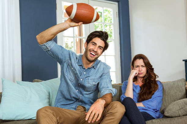 pareja viendo fútbol americano partido en la televisión - television boredom men sofa fotografías e imágenes de stock