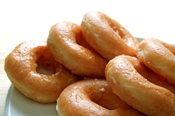 istock Piled up sugar-glazed doughnuts served on white plate 675365090