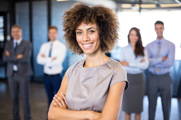 istock Businesswoman smiling at camera while her colleagues standing in background 675368366
