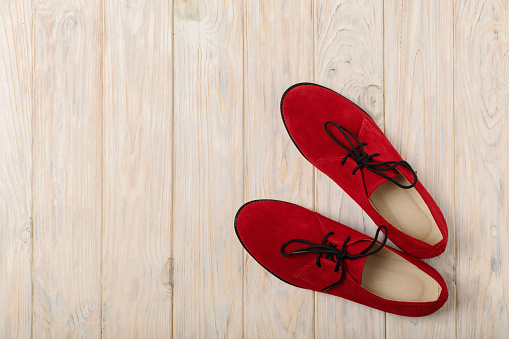 Red women's shoes oxfords on a light wooden background. Selective focus.