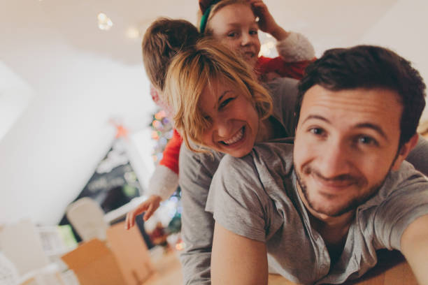 Our family photo on Christmas morning Christmas photo of a young family with two kids on Christmas morning, lying one on the top of another being cheerful and happy // self portrait rudolph the red nosed reindeer photos stock pictures, royalty-free photos & images