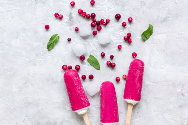 istock ice, red berries and popsicle on stone background top view 675389388