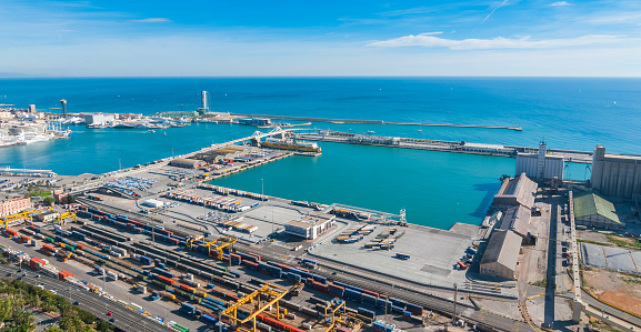 Bright sunny day on the industrial shipping & transport hub & railyard in Barcelona.  Modern cityscape & coastline of Spain.