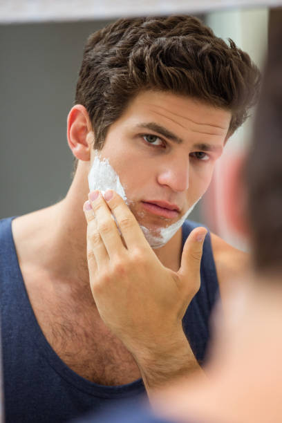 istock Young man applying shaving foam on his face 675408906