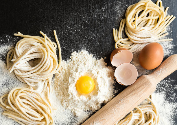 istock Raw homemade pasta with ingredients on black backgroun 675409072