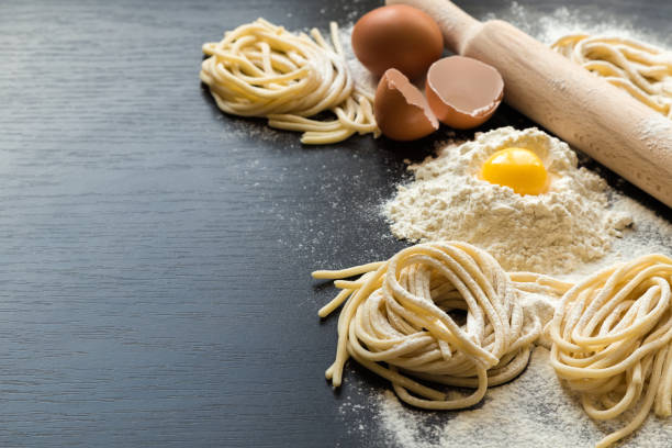 istock Raw homemade pasta with ingredients on black background 675409078