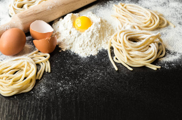 istock Raw homemade pasta with ingredients on black background 675409092