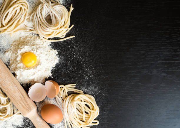 istock Raw homemade pasta with ingredients on black background. 675409116