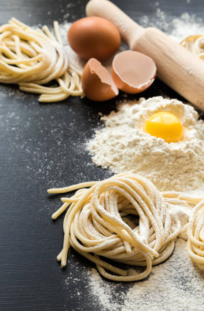 istock Raw homemade pasta with ingredients on black background 675409124