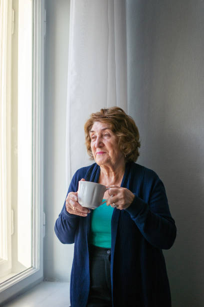 istock Senior woman drinking coffee by the window 675412286