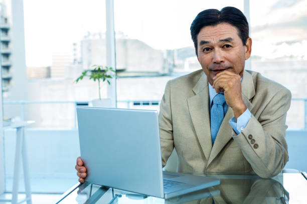 istock Smiling asian businessman working on laptop 675415876