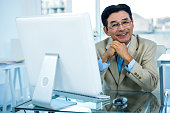 コンピューターで作業して笑顔のアジア系のビジネスマン