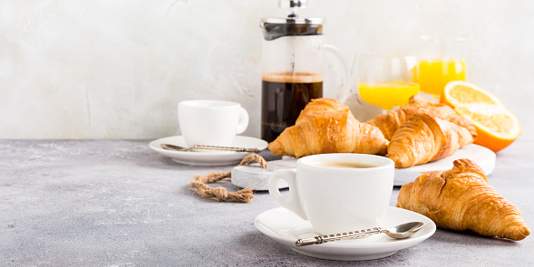 Healthy breakfast with coffee, croissants and orange juice on light gray background, selective focus, copy space.