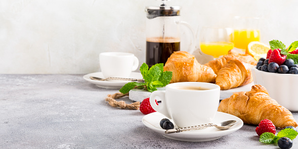 Healthy breakfast with coffee, croissants, fresh berries and orange juice on light gray background, selective focus, copy space.