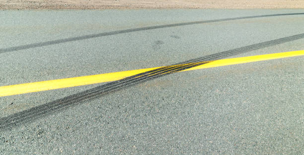 Black Skid Marks Black skid marks on a highway. The marks cross the center line. Low angle closeup view. street skid marks stock pictures, royalty-free photos & images
