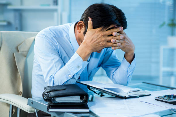 Worried businessman working at his desk Worried businessman working at his desk in office head in hands stock pictures, royalty-free photos & images