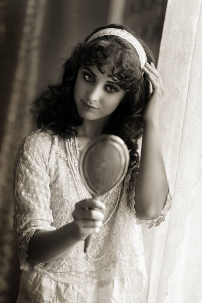 istock Retro woman looking at herself in a silver hand mirror 675426344