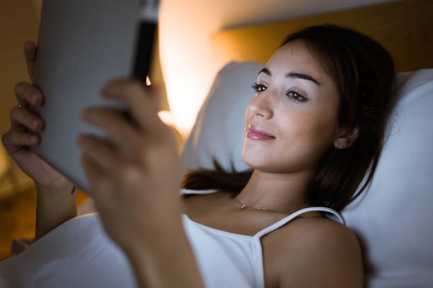 istock Beautiful young woman using her digital tablet in the bed at night. 675439446