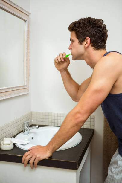 istock Young man brushing his teeth in bathroom 675443336