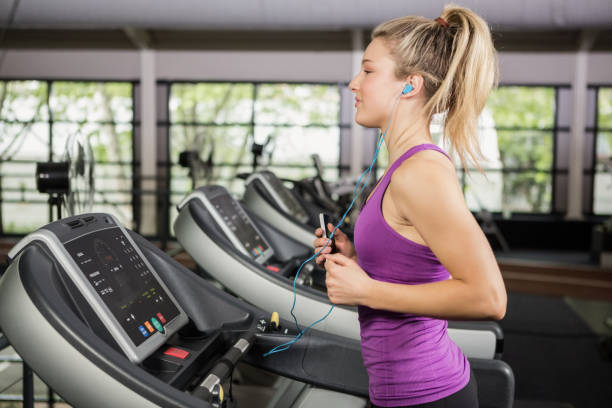 woman listening to music while jogging on the thread mill - run of the mill imagens e fotografias de stock