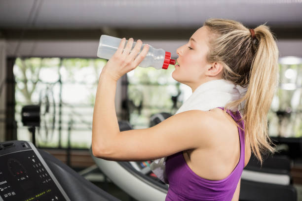 istock Woman on treadmill drinking water at gym 675448820