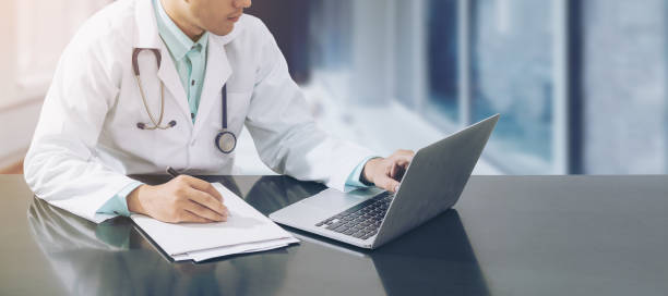 Doctor working on desk with laptop