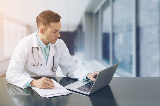 istock Doctor working on desk with laptop 675458898
