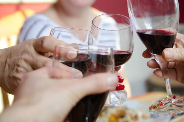 istock Close up on 4 hands toasting with red wine glass 675462582