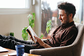 Young man reading a book at home