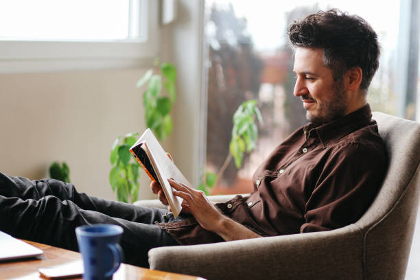 Young man reading a book at home stock photo