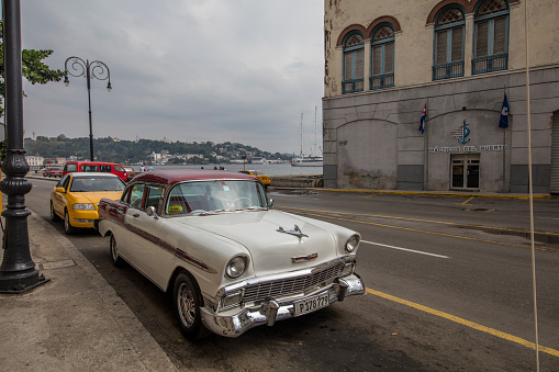 Vintage car is parking on the street. Incidental people on the background.