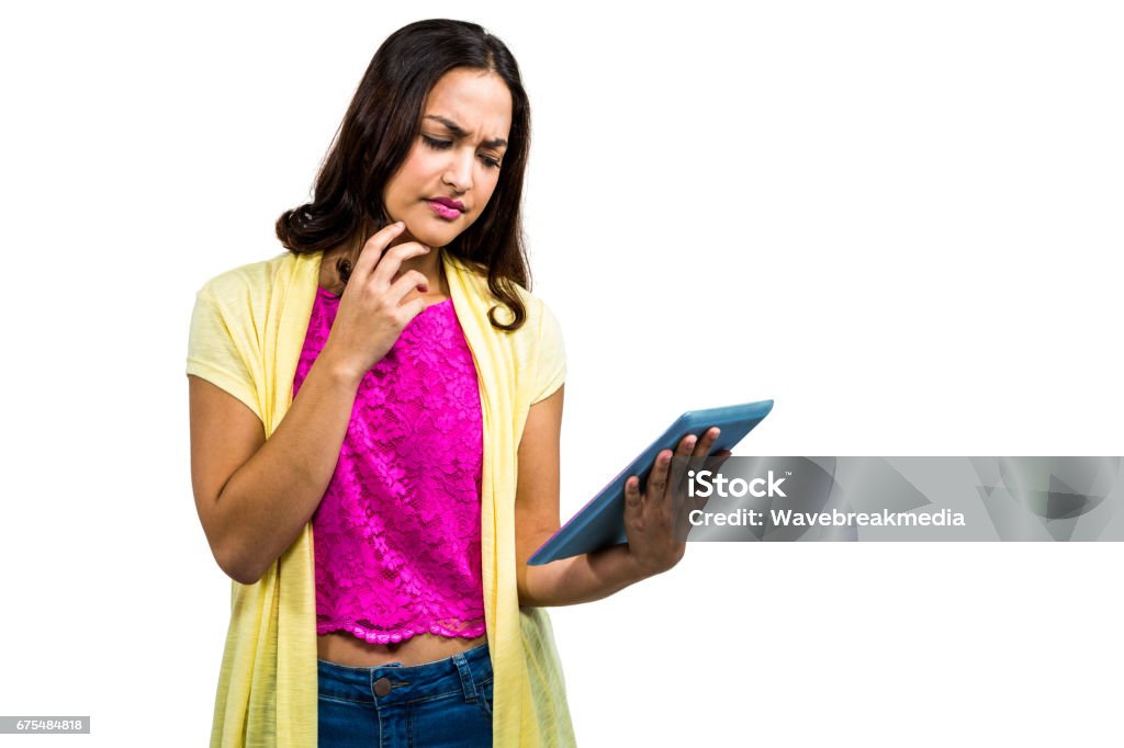 Confused woman using digital tablet Confused woman using digital tablet while standing on white background 20-24 Years Stock Photo