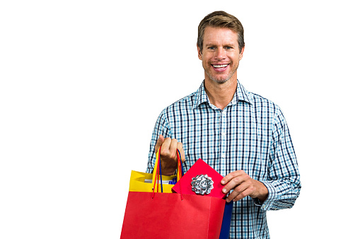 Portrait of happy man holding shopping bags against white background