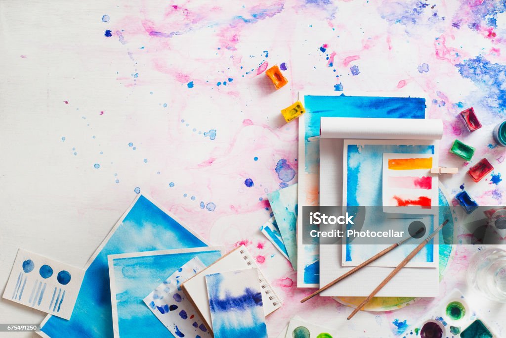 Feminine artist workplace with watercolor and notepads Creative artist workplace with watercolor, sketches and space for text Copy Space Stock Photo
