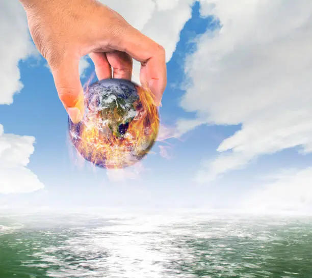Climate change,Global warming, fire global put in water, safe the earth conceptMan holding a globe in his hands. give the earth to human on sky background