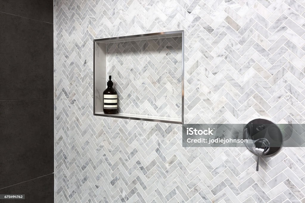 Shower shelf detail in wall of herringbone marble tiles Shower shelf detail in wall of herringbone marble tiles in a luxury new home Shower Stock Photo