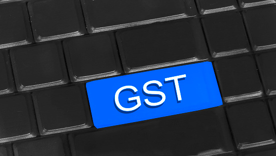 GST - Goods and Services Tax written on keyboard. Goods and Services Tax (GST) is an indirect taxation in India merging most of the existing taxes into single system of taxation. It will be replacing all other taxes from July, 01 - 2017.