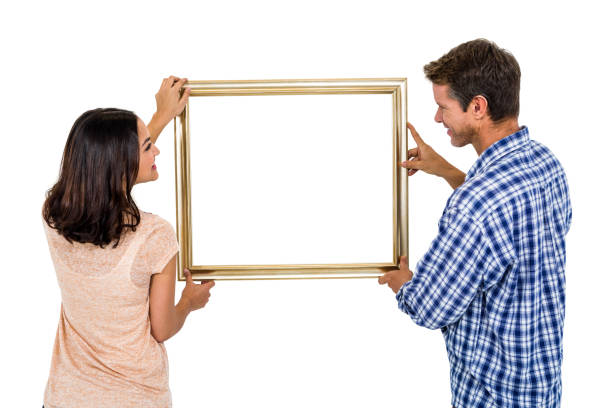 happy couple holding picture frame - love hanging indoors studio shot imagens e fotografias de stock