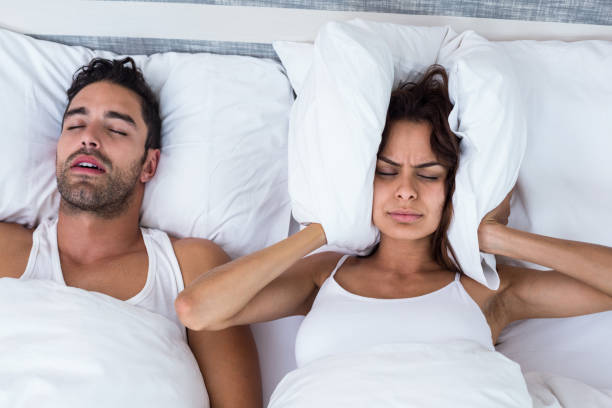frau blockieren ohren während mann schnarchen auf bett - couple love snoring sleeping stock-fotos und bilder