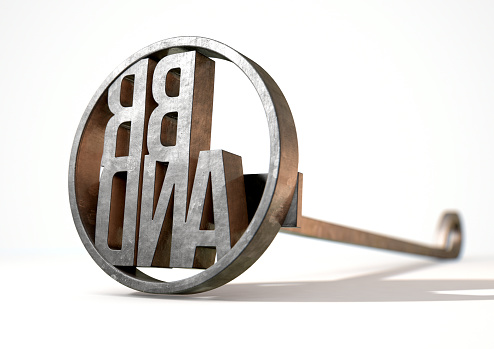 A metal cattle branding iron with the word brand as the marking area on an isolated white surface - 3D render