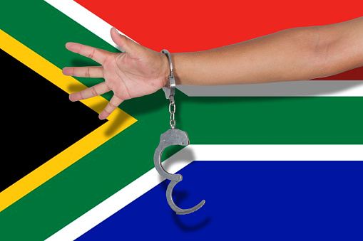 handcuffs with hand on South Africa flag