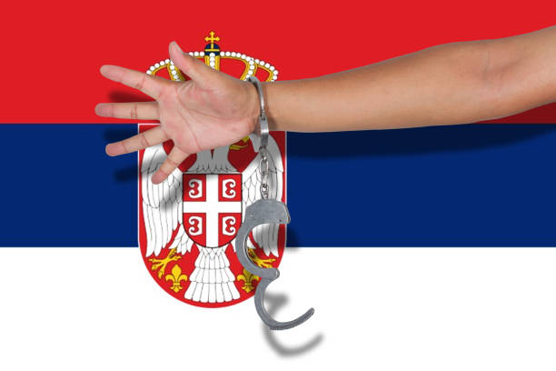 istock handcuffs with hand on Serbia flag 675523386