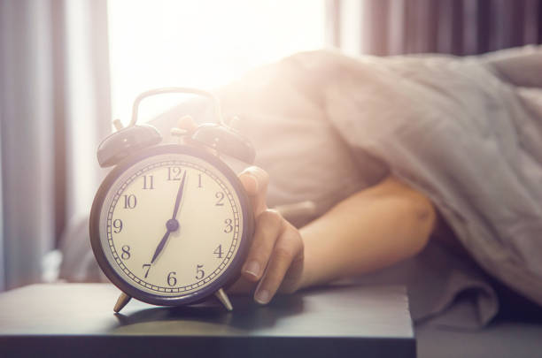 istock Sleepy young woman trying kill alarm clock 675523612