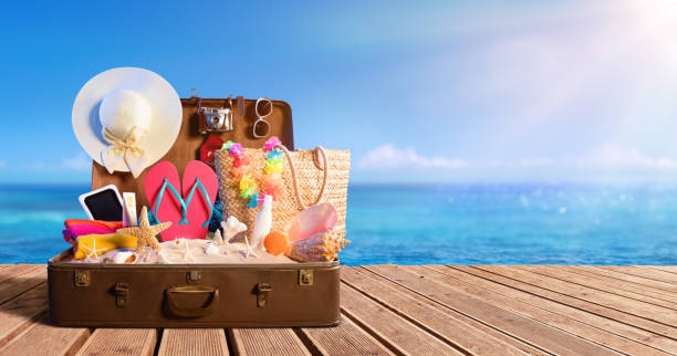 Beach Accessories In Suitcase On Beach - Travel Concept Full Suitcase On Wooden Deck packing stock pictures, royalty-free photos & images