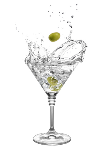 martini in glass with splashes and olives isolated on white background. Green olive is falling in the alcohol cocktail. Splash of martini from the falling olives