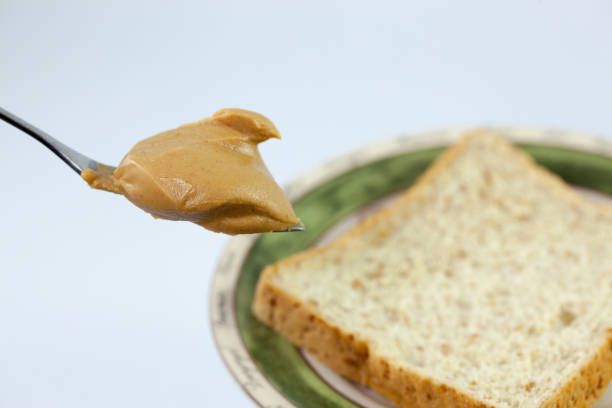 istock Creamy peanut butter in a spoon and bread 675539210