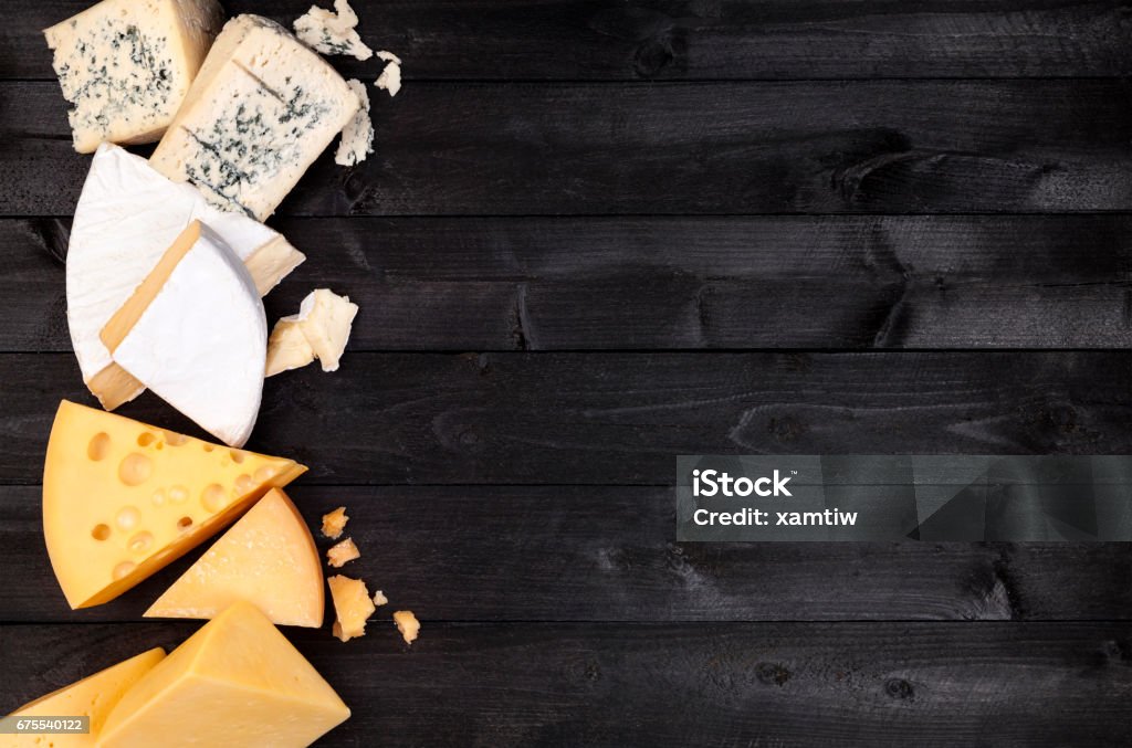 Different types of cheese on black wooden table. Top view Various types of cheese on black wooden table background. Cheddar, parmesan, emmental, blu cheese. Top view, copy space. Cheese Stock Photo